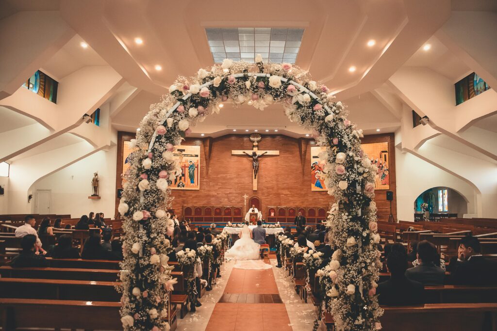 A captivating wedding ceremony inside a church featuring a floral archway and seated guests.