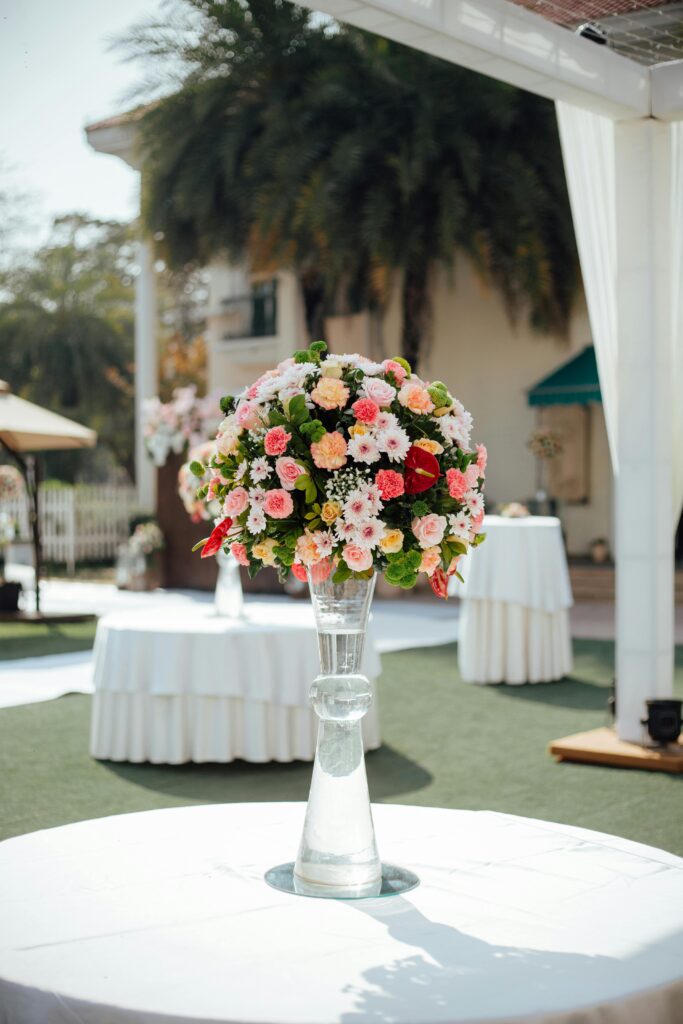 Beautiful wedding reception setup featuring a colorful floral centerpiece in an outdoor setting.