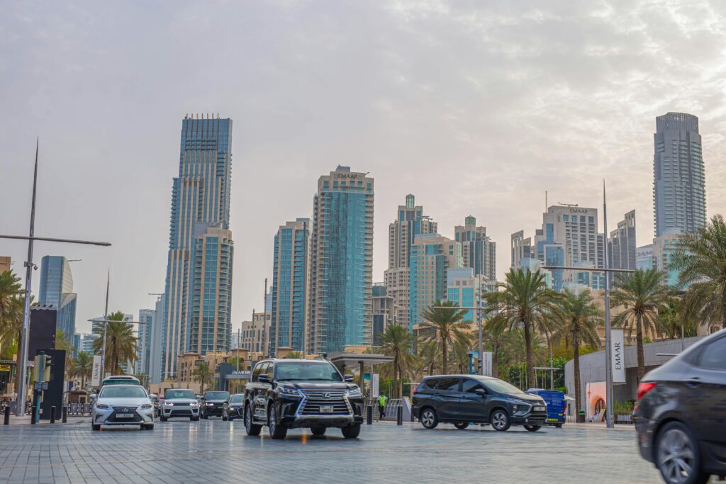Dubai's towering skyscrapers against a bustling road, highlighting urban life.